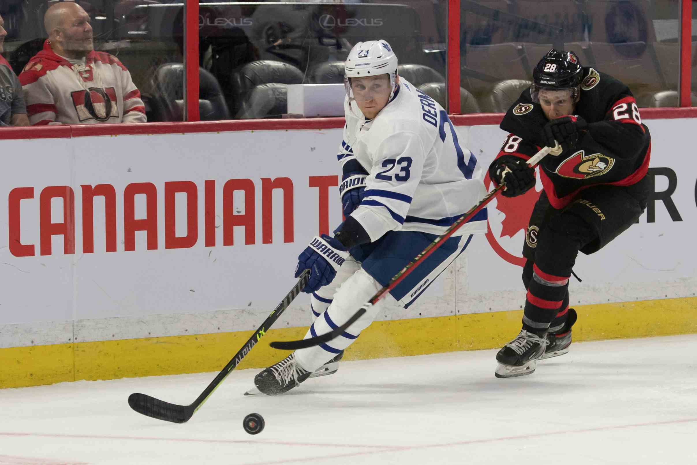 Leafs Travis Dermott and Senators Connor Brown battle for puck in game at Canadian Tire Centre